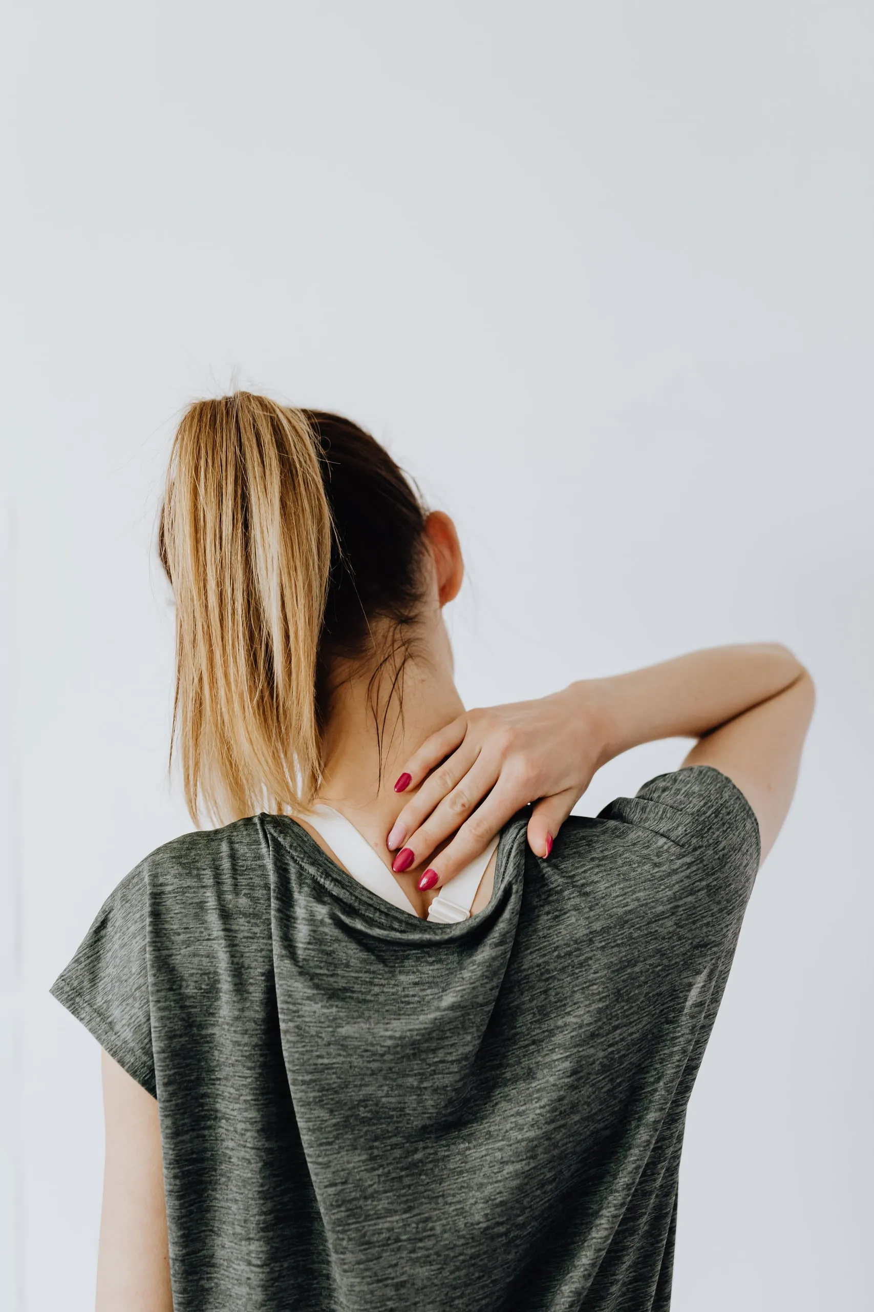 A woman holds her neck and shoulder