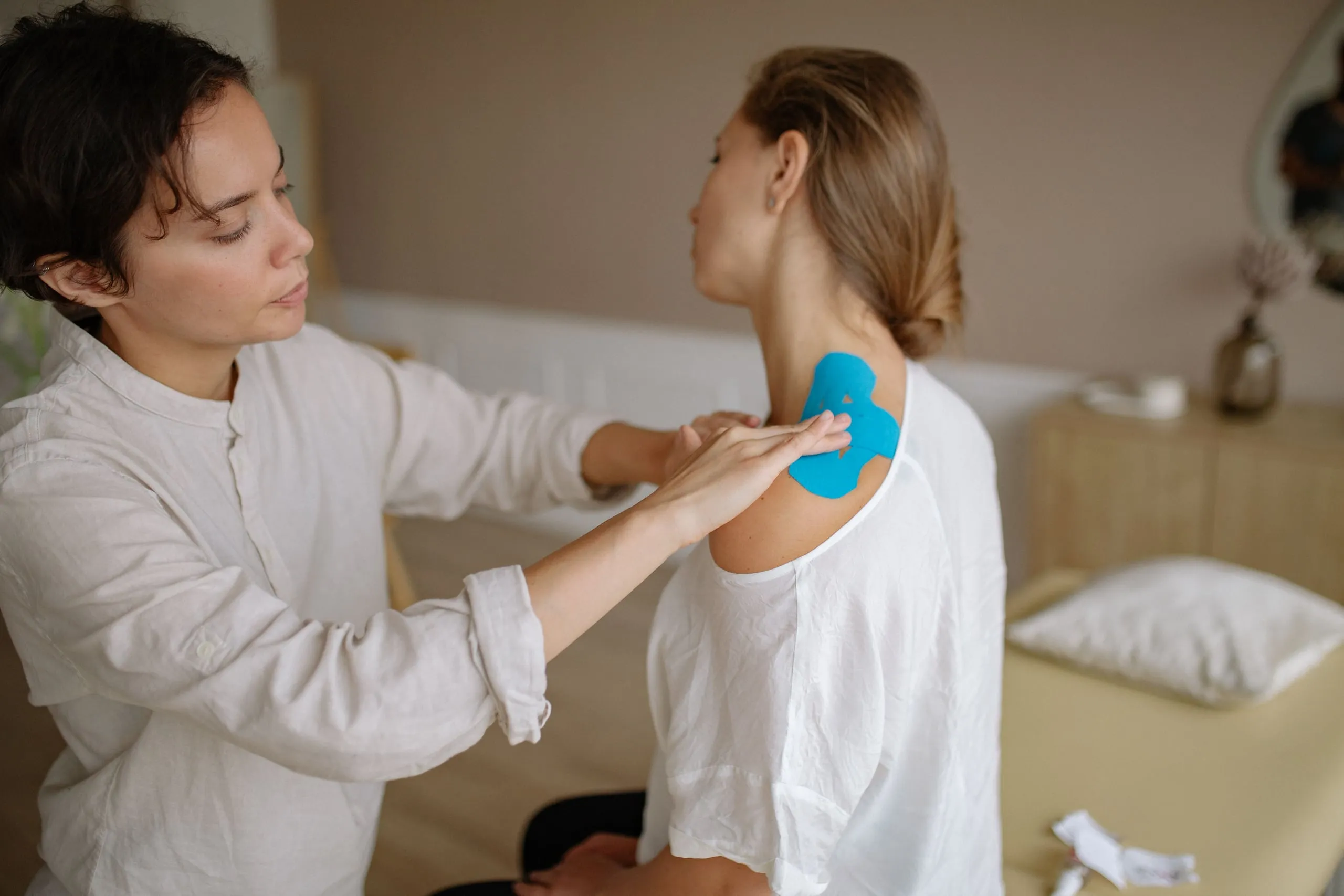 A physical therapist tapes a woman's shoulder