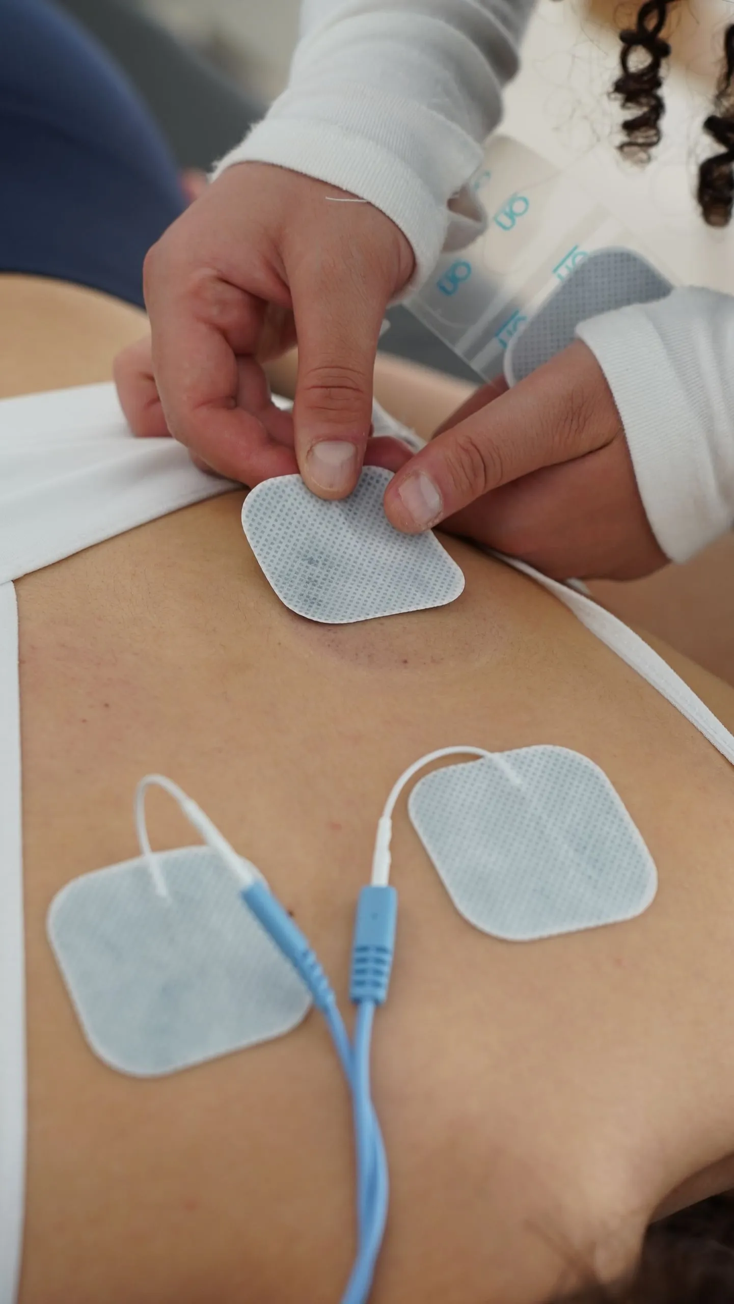 Hands place TENS electrode pads on a lower back