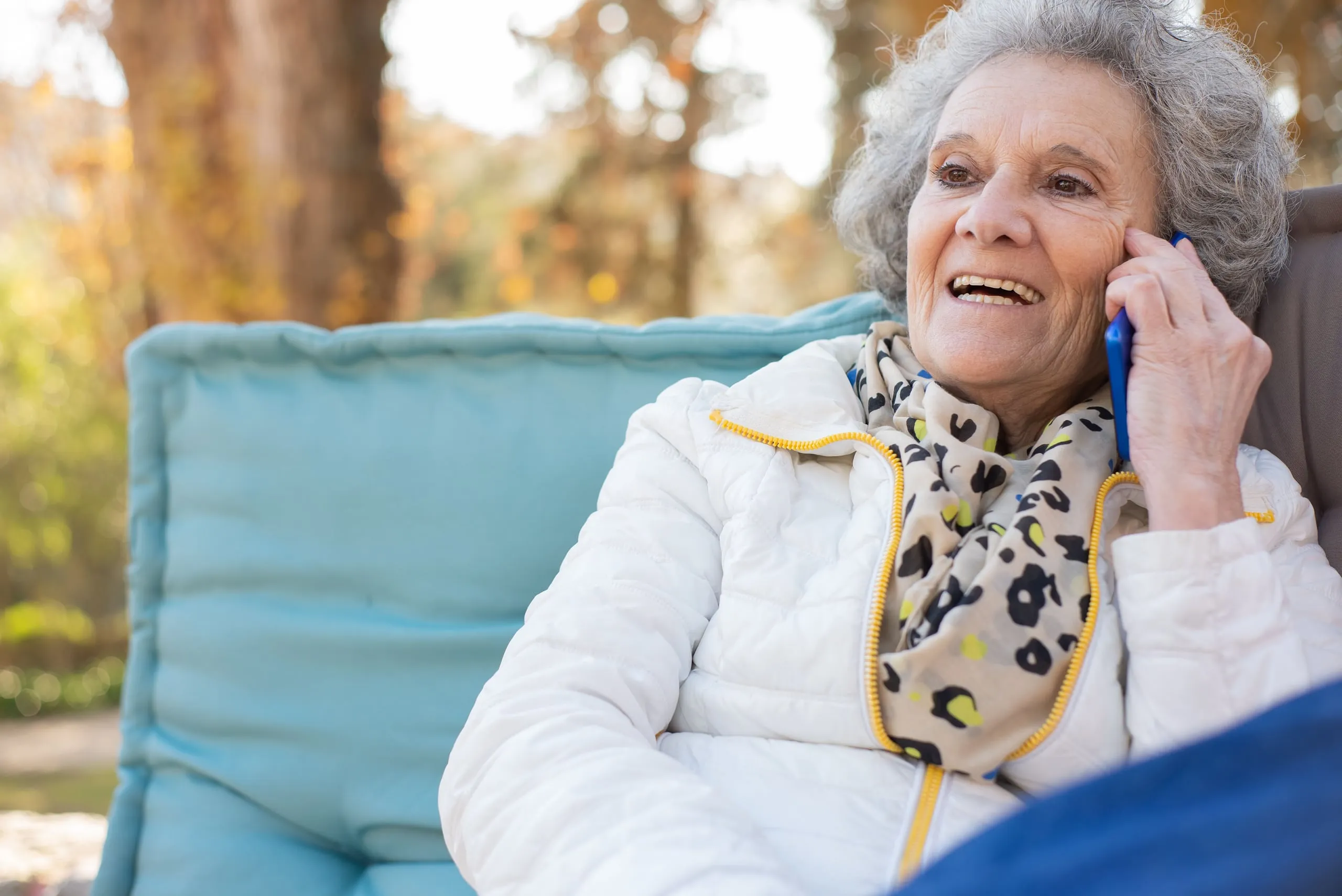 An older woman smiles while talking on the phone