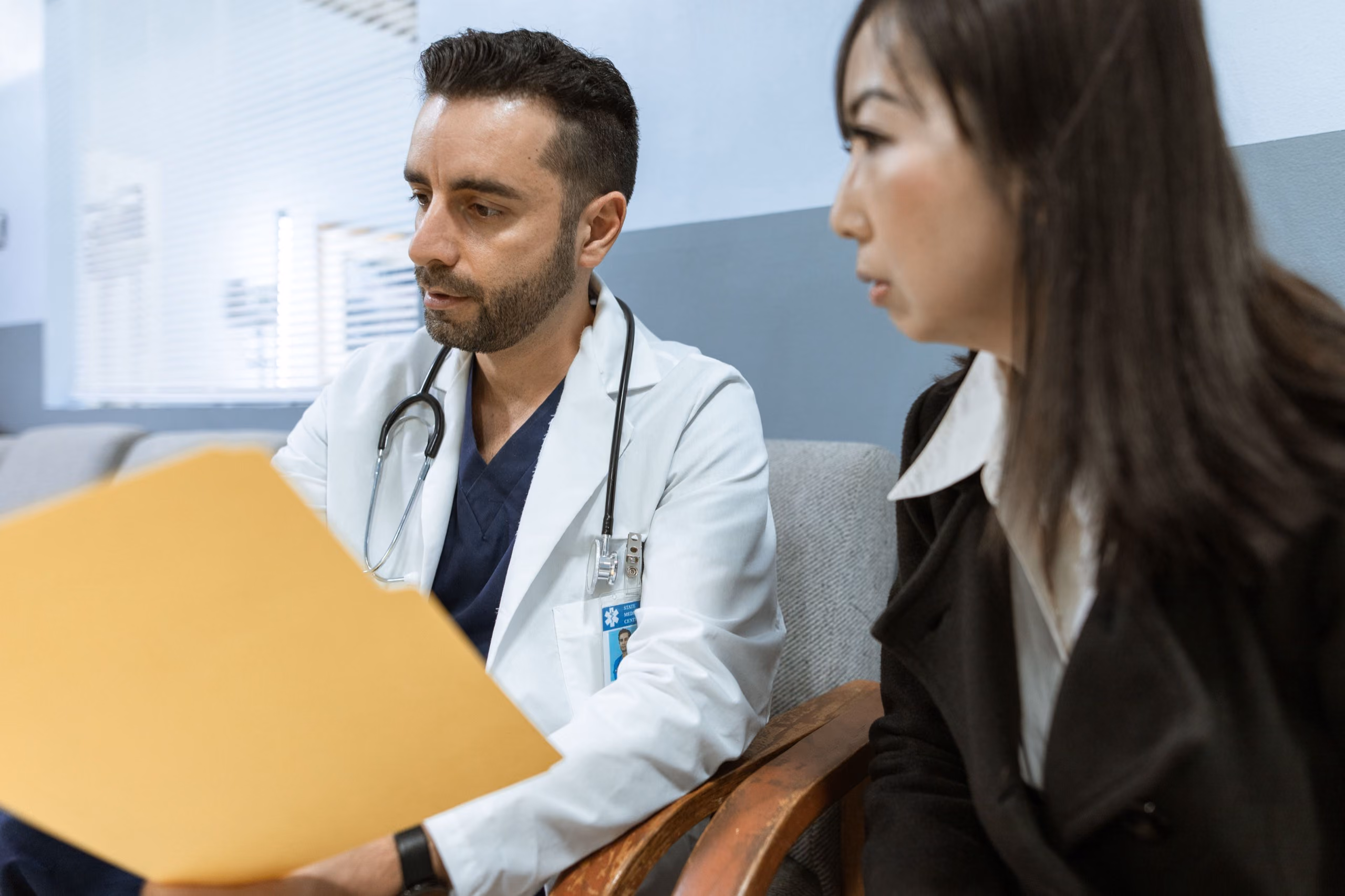 A doctor holding a folder talks with a patient