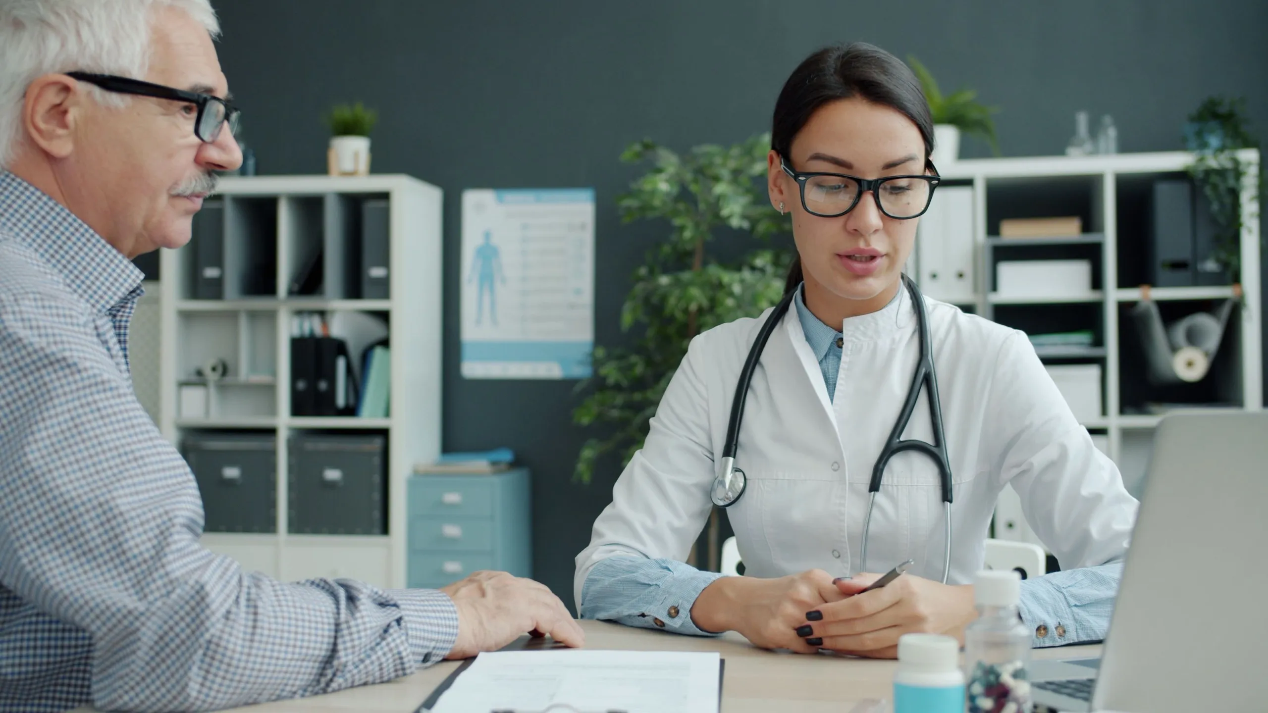 A doctor talks with an older man across her desk