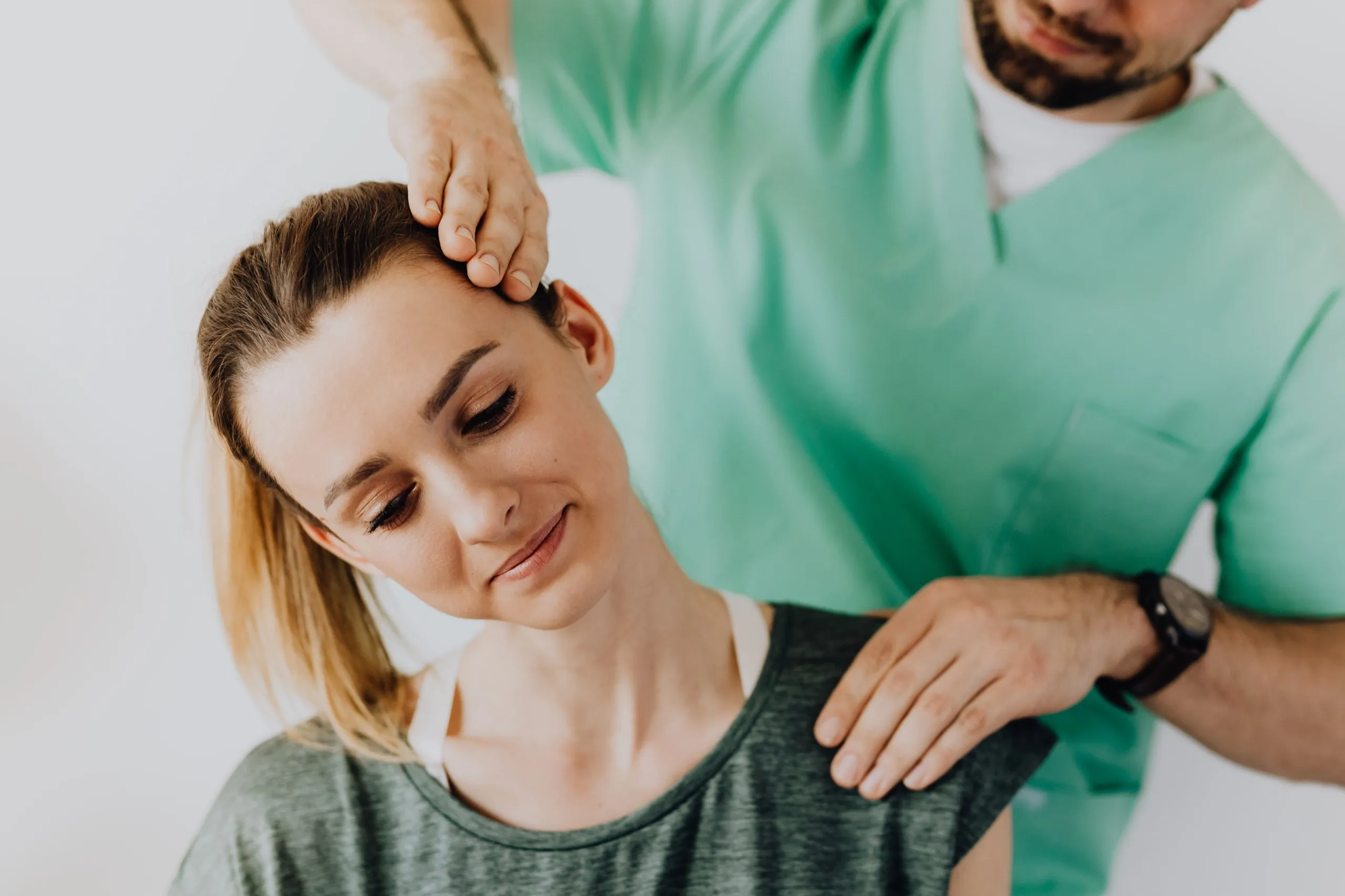 A therapist checks a woman's neck and shoulder