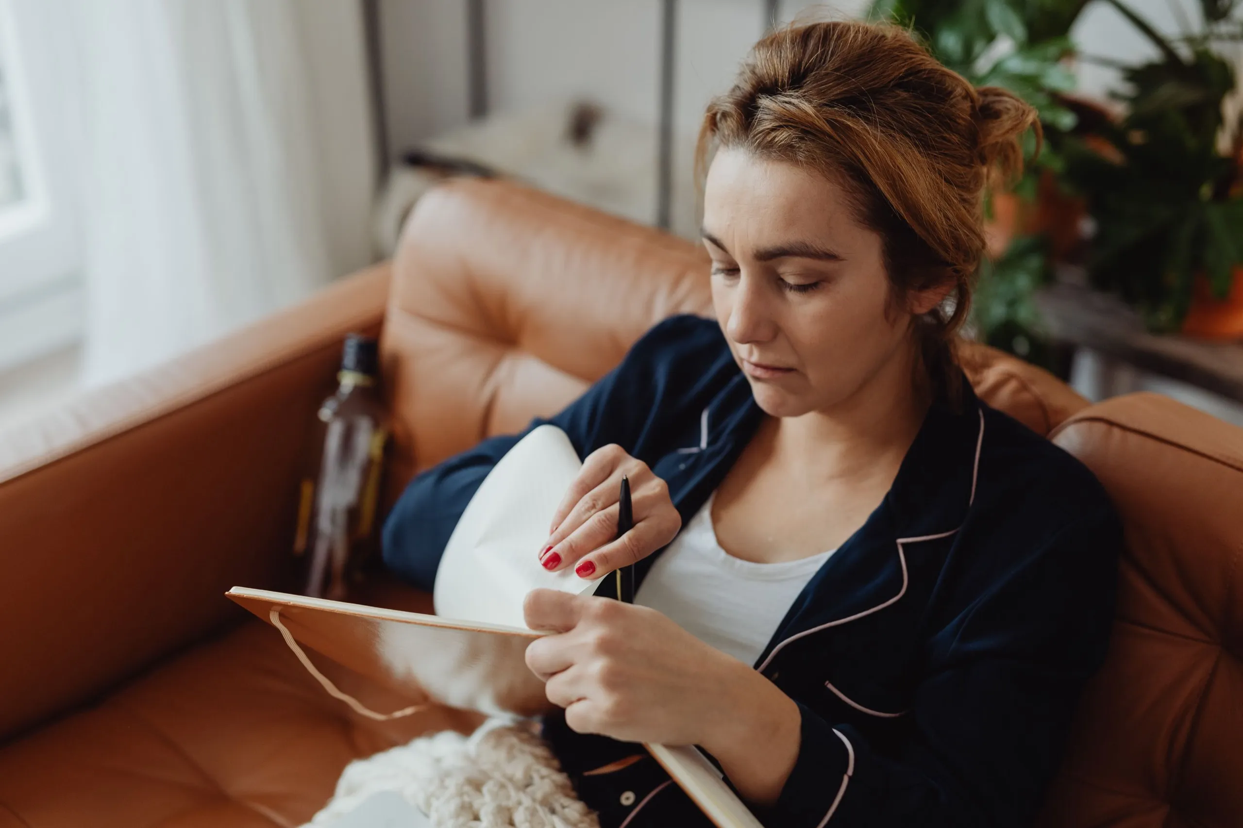 A woman writes in a notebook on her sofa
