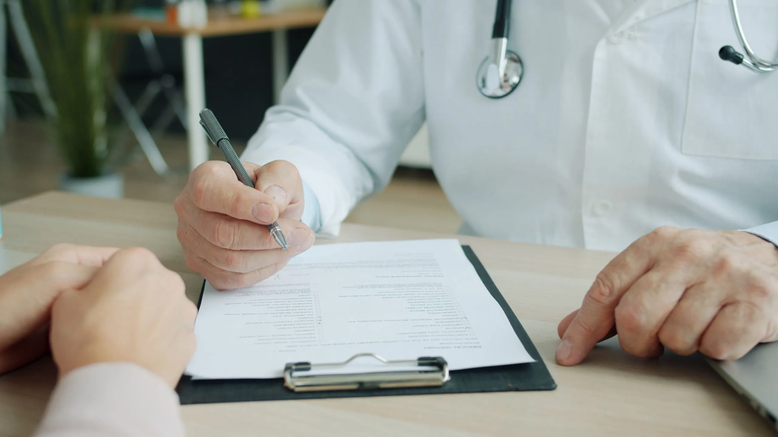 A doctor signs a form on a clipboard